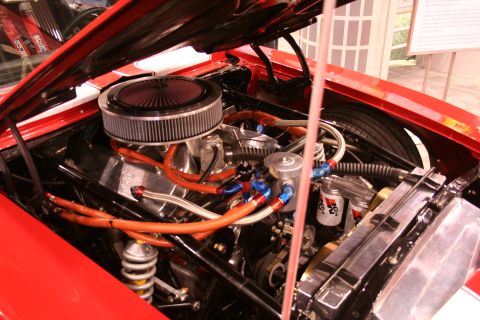 Detailed V8 engine bay of a red show car with orange plug wires