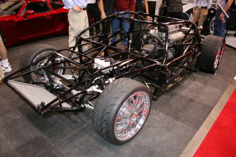 Bare tubular space-frame chassis with mid-mounted engine on display
