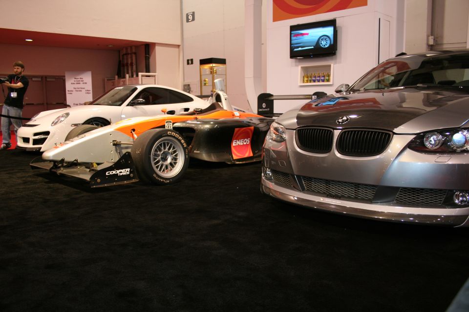 Race cars on display including a prototype and a silver BMW coupe