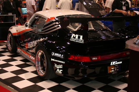 Black Hankook-liveried Porsche 911 race car on checkered floor, rear view