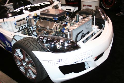 White roadster with exposed engine and radiator at an auto show