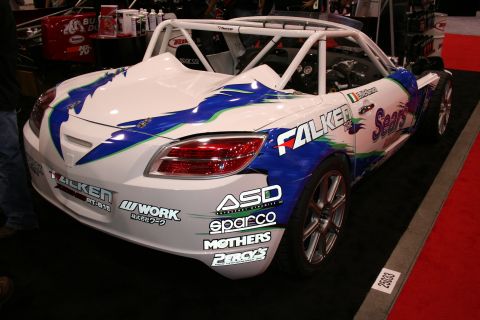 White and blue Falken-livery roadster race car, front quarter view