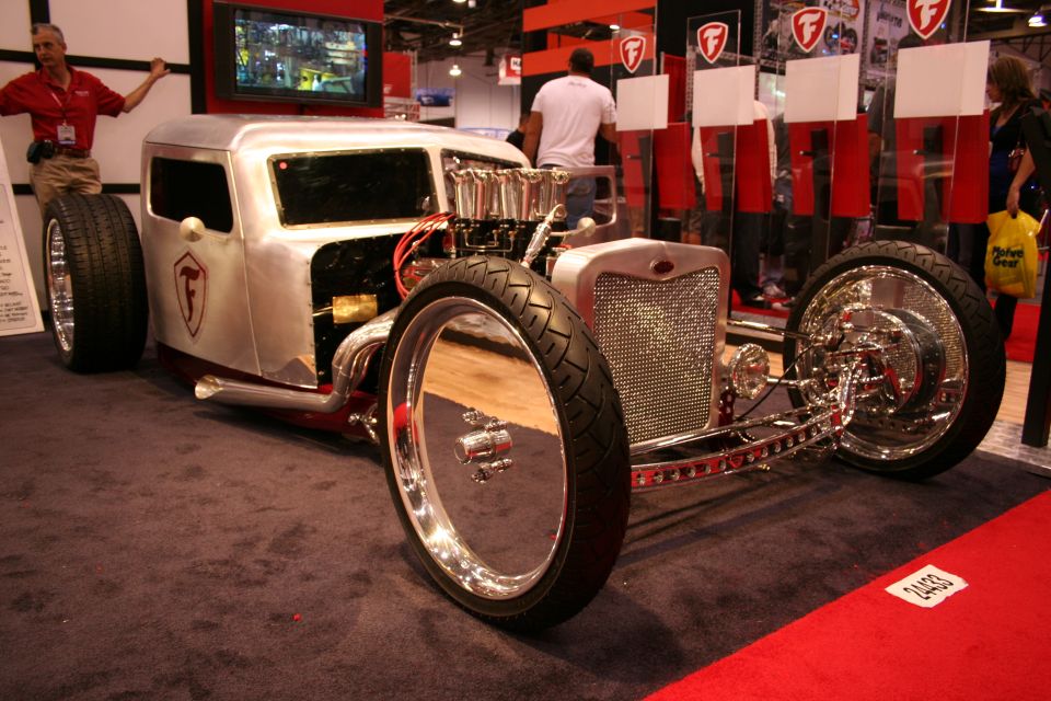 Custom hot rod with exposed engine and large rear tires, indoors