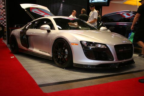 Silver Audi R8 sports car with butterfly doors open, parked on a red carpet. Text on the grille reads 'R8 RAZO