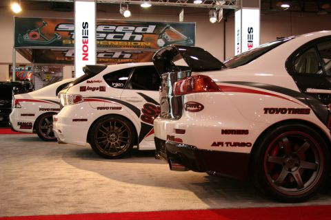 Rear view of white race cars with racing decals and spoilers