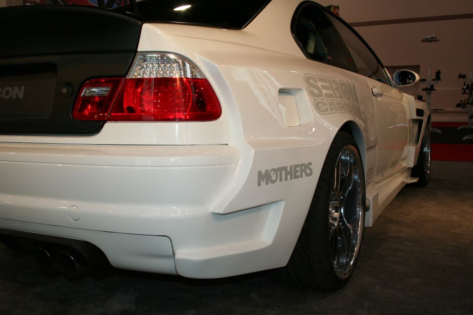 White modified BMW M3 rear quarter panel with "MOTHERS" decal and carbon fiber trunk lid