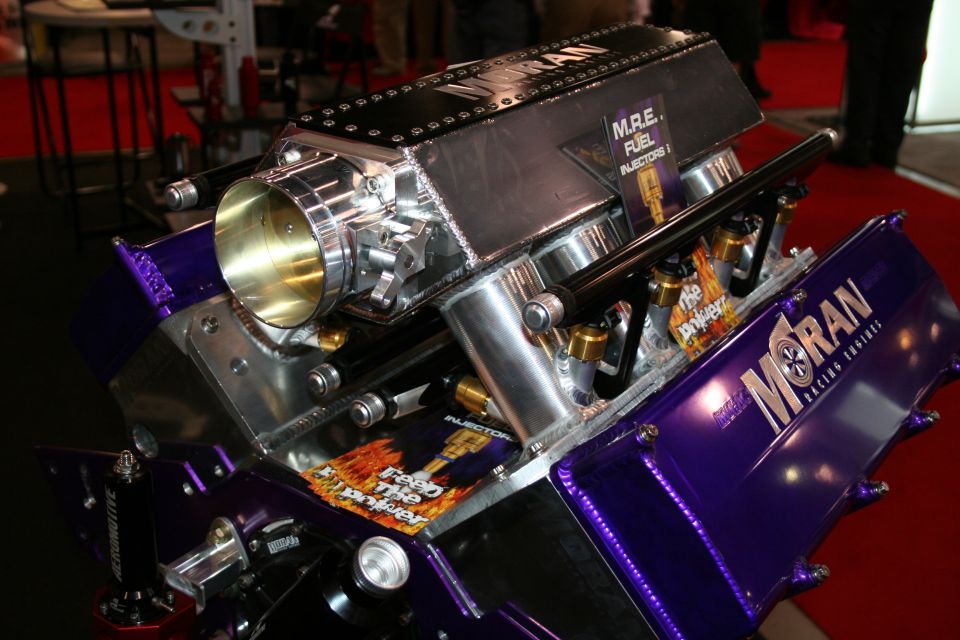 Custom racing engine with purple valve covers and a large intake manifold. Text on the engine reads 'MORAN Racing Engines'