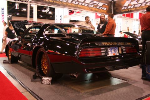 Black Pontiac Trans Am with gold wheels and custom hood art