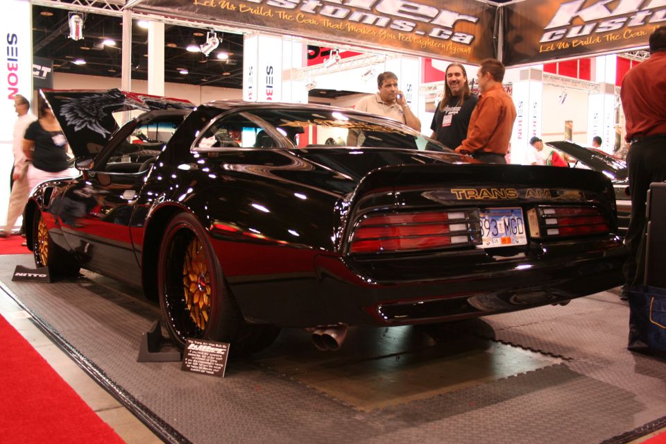 Black Pontiac Trans Am with gold wheels and custom hood art