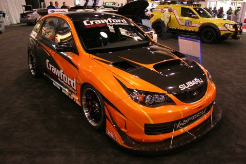 Orange and black Subaru WRX STI with racing decals and a large rear wing