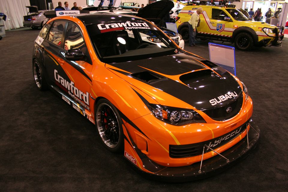 Orange and black Subaru WRX STI with racing decals and a large rear wing