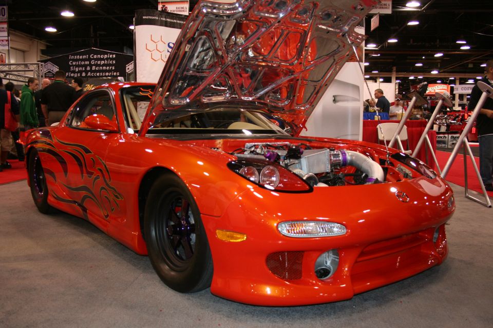 Orange sports car with black flame decals and hood open, showing engine
