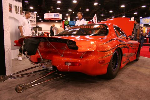 Orange drag car with large rear wing and drag slicks