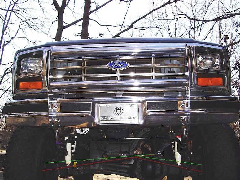 Front view of lifted Ford truck with chrome grille and drawn lines showing tie rod flip geometry