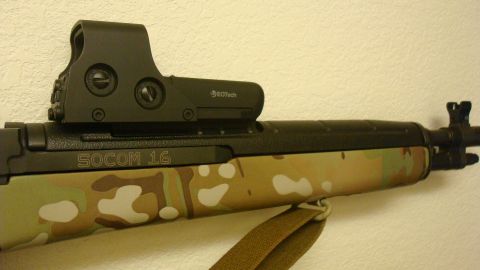 1990 Ford Bronco - Rifle with SOCOM 16 marking and EOTech sight mounted on a camouflage stock.