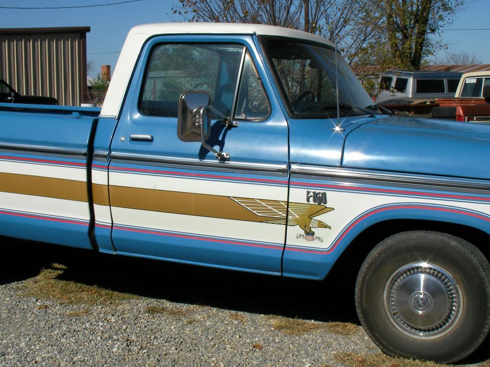 Side view of a blue and white pickup truck with an eagle graphic and F-150 badging