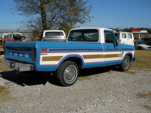 1976 Ford F-150 - This 1976 Ford F-150 Custom pickup truck is seen in a gravel lot with other vehicles in the background.