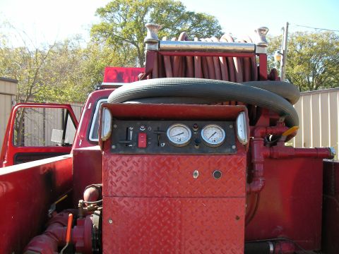 1979 Ford F-350 - Close-up of a red fire truck's control panel, gauges, switches, and a large coiled hose assembly.