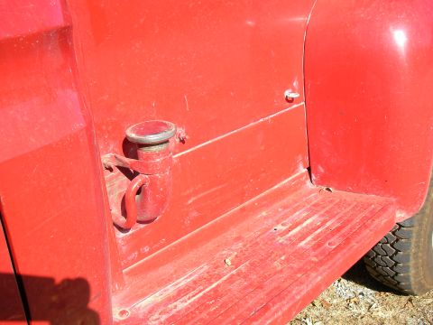 1979 Ford F-350 - Close-up of a red truck's exterior, showing a fuel filler cap and step plate.