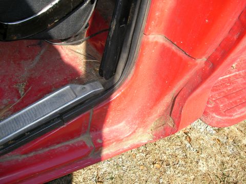 1979 Ford F-350 - The interior door sill of a red vehicle shows signs of wear and accumulated dirt.
