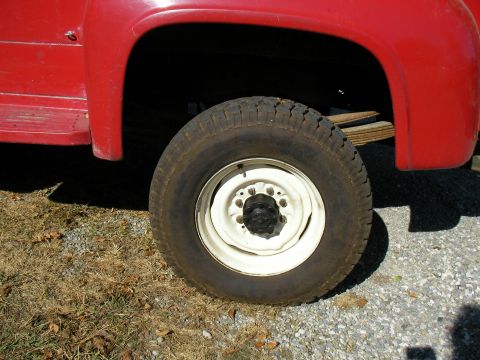 1979 Ford F-350 - Close-up view of a red truck's wheel and fender, showing the tire and part of the bodywork.
