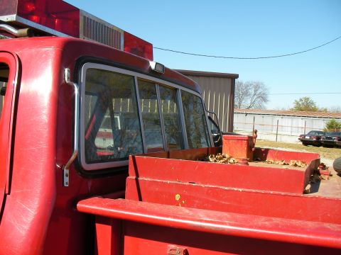 1979 Ford F-350 - A red pickup truck with emergency lights is parked outdoors next to other vehicles and buildings.