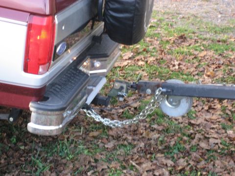 1996 Ford Bronco - Close-up of the rear of a red and silver pickup truck, showing its trailer hitch and safety chains.