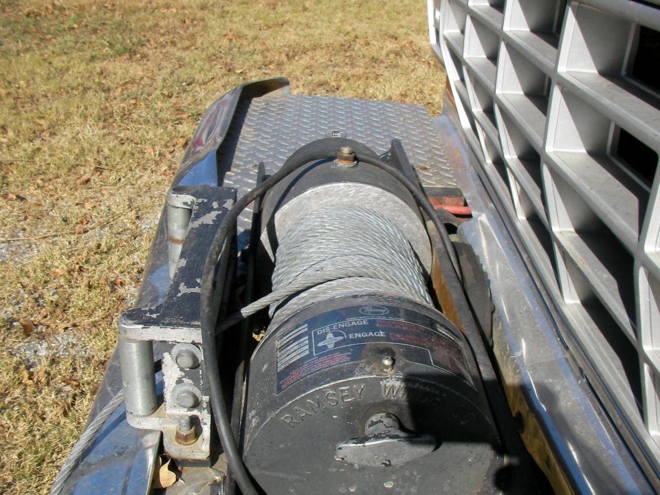 Ramsey winch with "DIS-ENGAGE" and "ENGAGE" labels, mounted on a diamond plate surface next to a vehicle grille