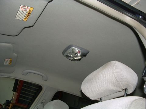 1999 Mercury Grand Marquis - Interior view of a car's ceiling light and headrest, with a warning label visible on the sun visor.