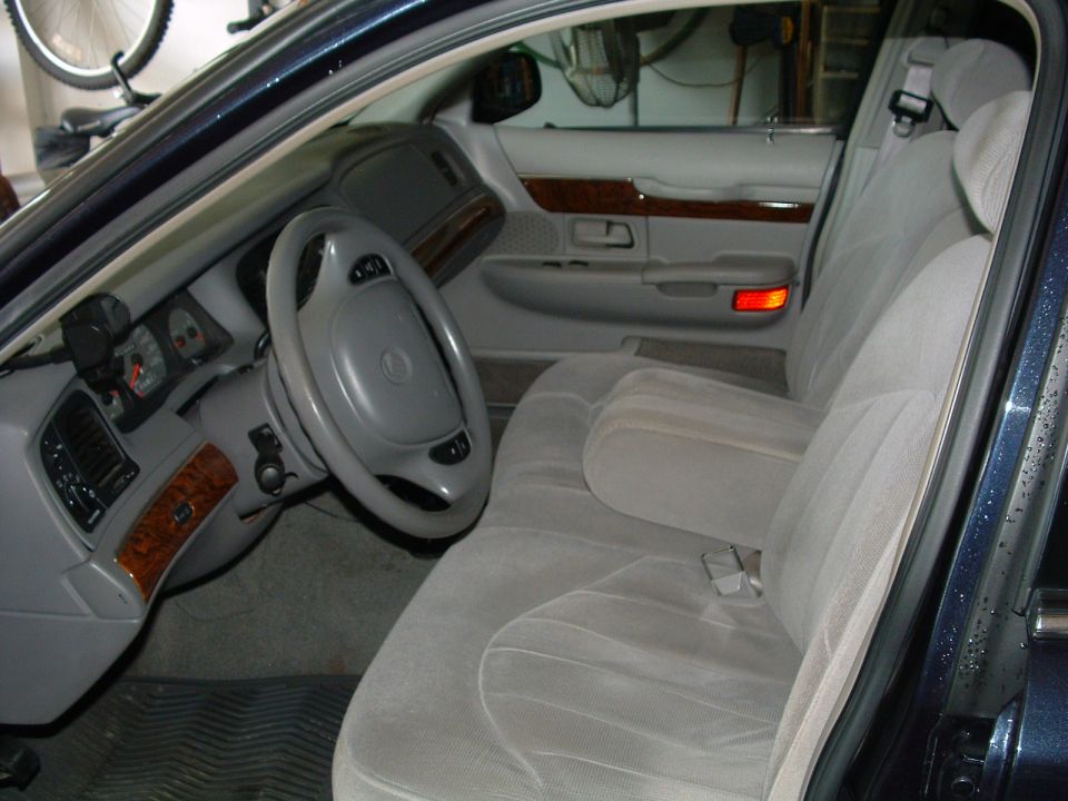 Interior shot of a 1999 Mercury Grand Marquis, showing the driver's seat, steering wheel, and dashboard