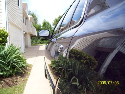 1999 Mercury Grand Marquis - Side view of a dark sedan, showing the door handle and a reflection of the surrounding environment.