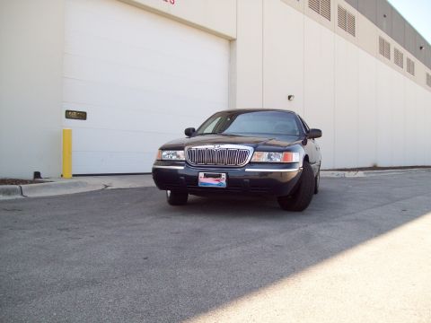 1999 Mercury Grand Marquis - Front view of a black 1999 Mercury Grand Marquis parked in front of a large white garage door.