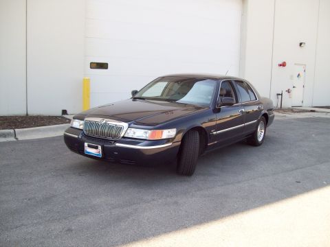 1999 Mercury Grand Marquis - Dark colored 1999 Mercury Grand Marquis parked in front of a large garage door.