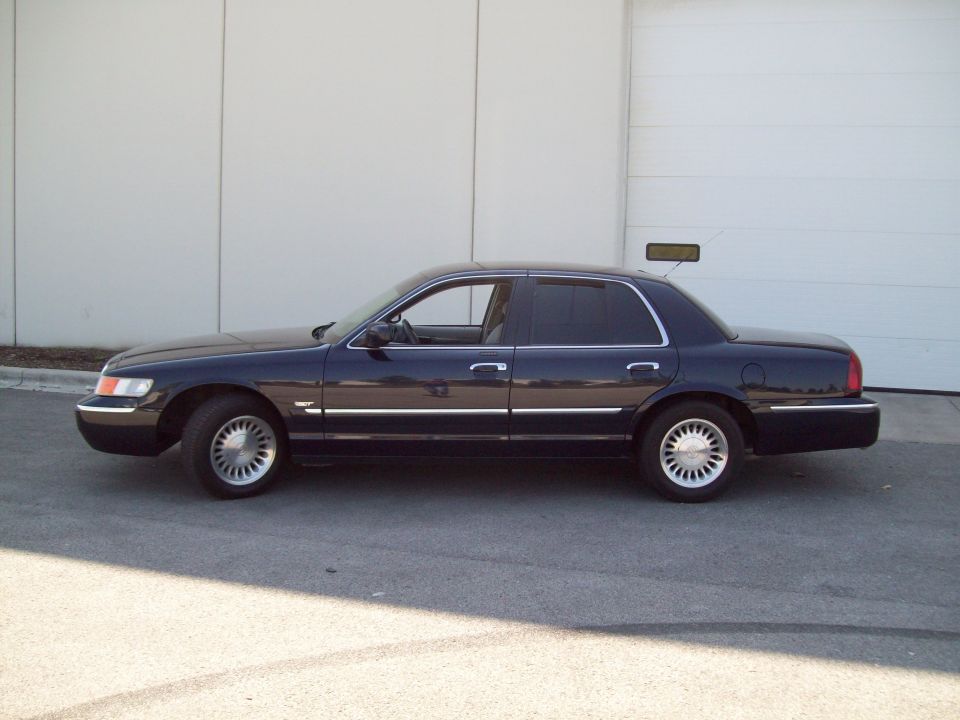 dark sedan parked outside a building, side view