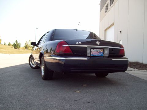 1999 Mercury Grand Marquis - Rear view of a dark blue Mercury Grand Marquis parked outdoors near a building.
