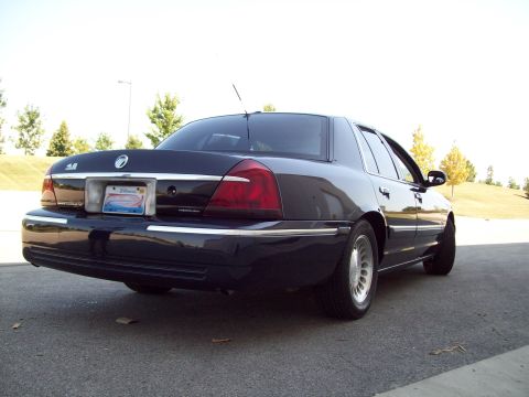 1999 Mercury Grand Marquis - Rear view of a dark sedan, possibly a Mercury Grand Marquis, parked outdoors.