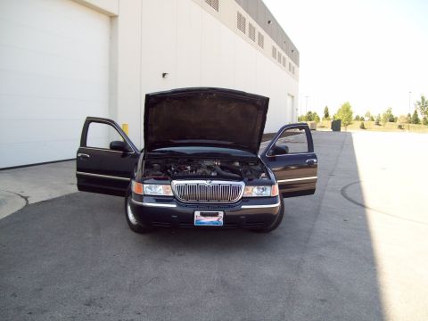 1999 Mercury Grand Marquis - A black sedan, likely from the early 2000s, is parked with its hood and front doors ajar, revealing the engine bay.
