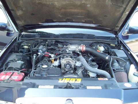 1999 Mercury Grand Marquis - Engine bay of a 1999 Mercury Grand Marquis, showing the V8 engine and aftermarket modifications.