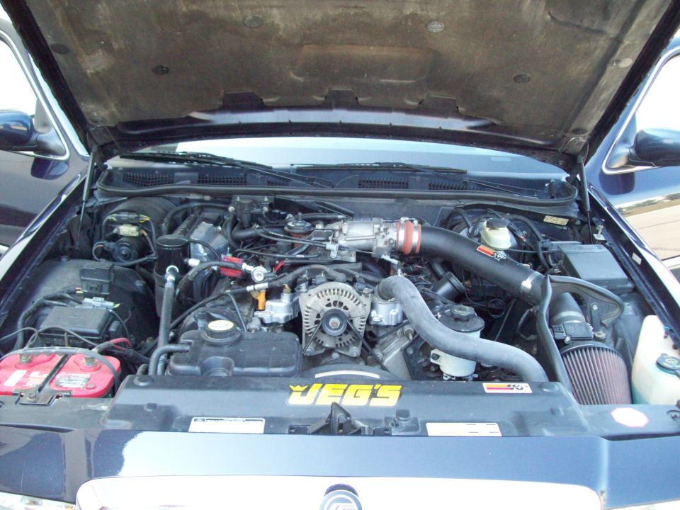 1999 Mercury Grand Marquis engine bay with aftermarket air intake and JEGS sticker on the radiator cover