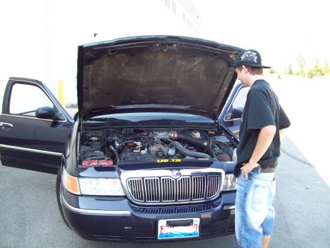 1999 Mercury Grand Marquis - A person inspects the engine of a Mercury Grand Marquis, which appears to be a 2000 model year.