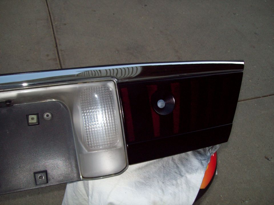 Close-up of a car's rear tail light assembly with a chrome trim piece above it