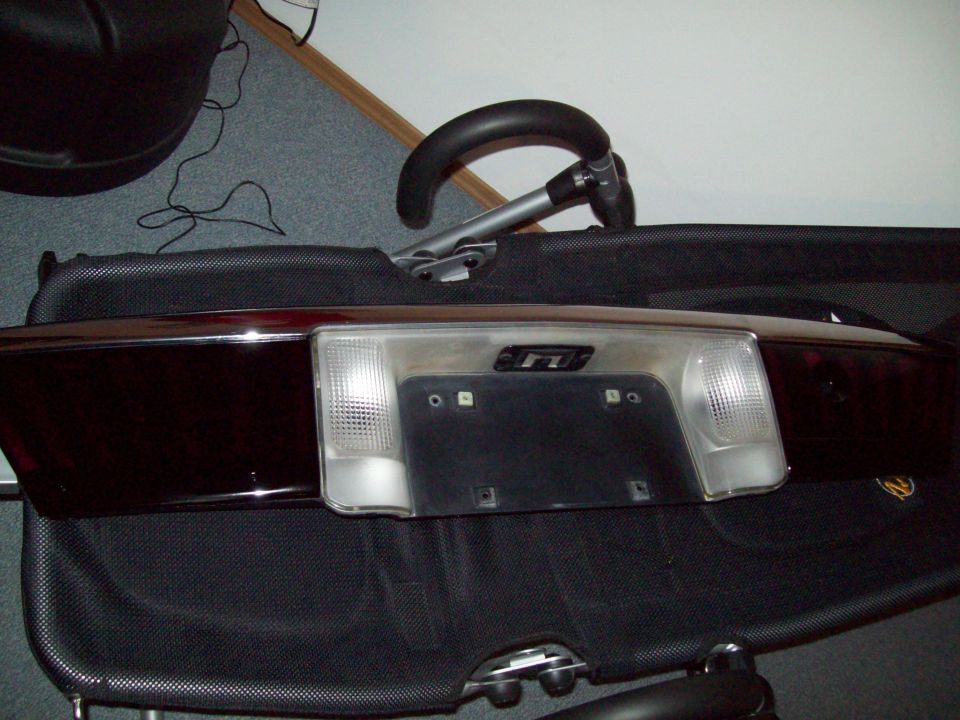 Removed dark rear license plate panel with clear backup lamps resting on a folding chair