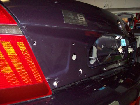 1999 Mercury Grand Marquis - Rear view of a dark purple car trunk lid, showing the "4.6 INTERCEPTOR" badge and the area where the taillight assembly was removed.