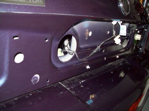 1999 Mercury Grand Marquis - Close-up of the rear of a metallic dark purple/blue sedan with the license-plate filler panel removed, exposing the bare sheet metal recess…