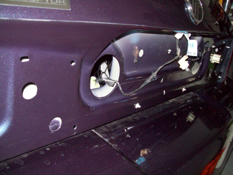Exposed rear plate recess with wiring harness and lamp socket on dark purple sedan