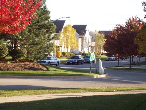 1999 Mercury Grand Marquis - Several cars are parked along a suburban street lined with houses and trees displaying fall colors.