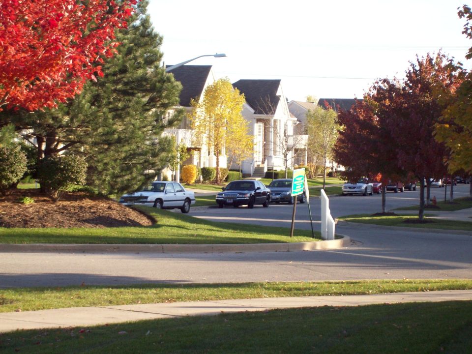Dark sedan parked on a street with fall foliage, front 3/4 view