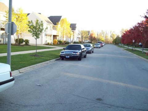 1999 Mercury Grand Marquis - Cars parked along a residential street during autumn.