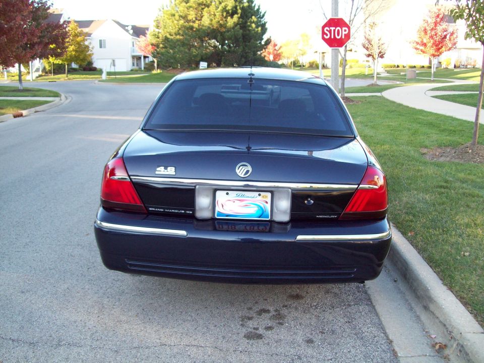 Dark blue Mercury Grand Marquis parked on a residential street, rear view. Has a "4.6" badge and Illinois plates