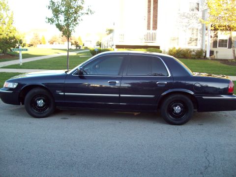 1999 Mercury Grand Marquis - Side profile of a dark blue 1999 Mercury Grand Marquis sedan parked on a residential street.